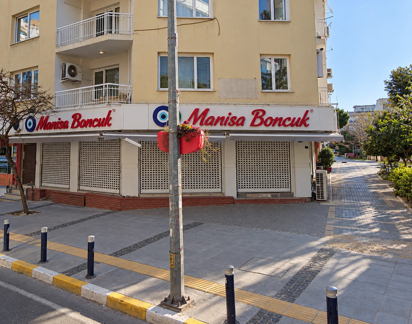 Manisa Boncuk mağazasının iki cephesini çevreleyen kırmızı kutu harf ve nazar boncuğu logolu tabela